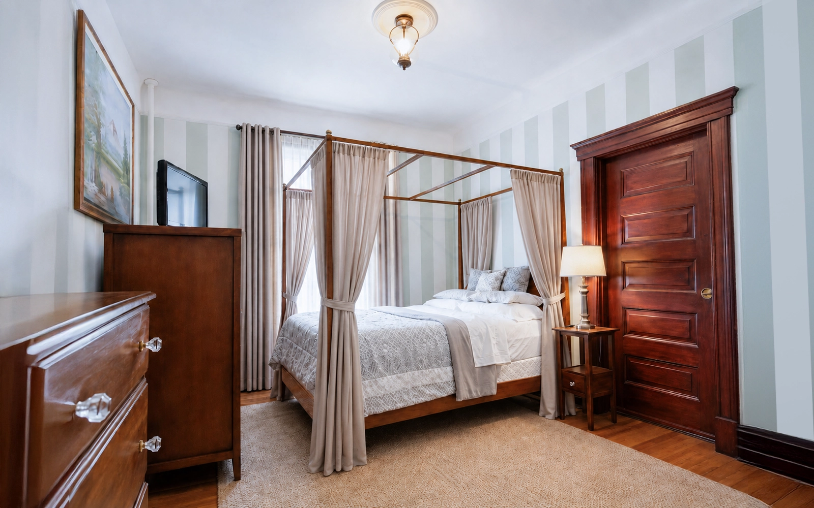 Idylease guest room with historic woodwork, canopy bed and striped walls